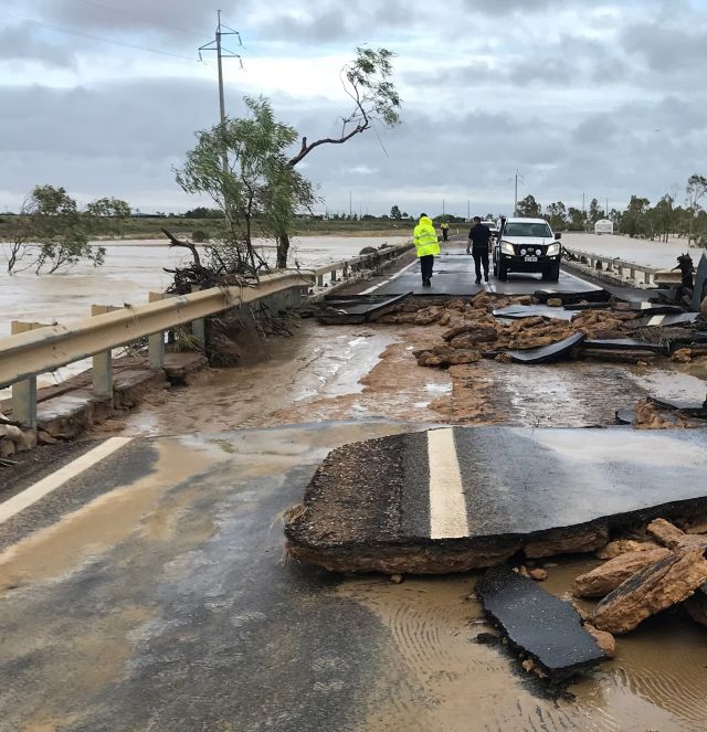 A bridge affected by a bad flood. It is covered in water and the road broken