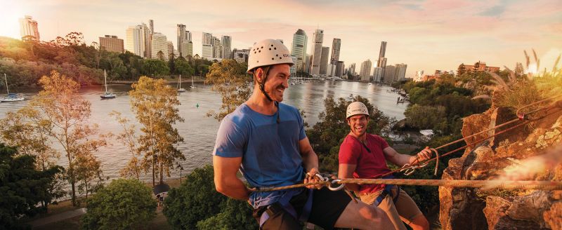 Two men happily abseiling down kangaroo point in Brisbane