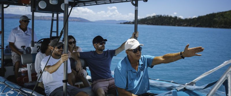 A group of people in a boat staring pensively out into the distance