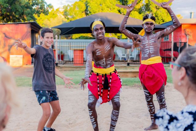 Two Indigenous dancers dressed traditionally and a teenage boy